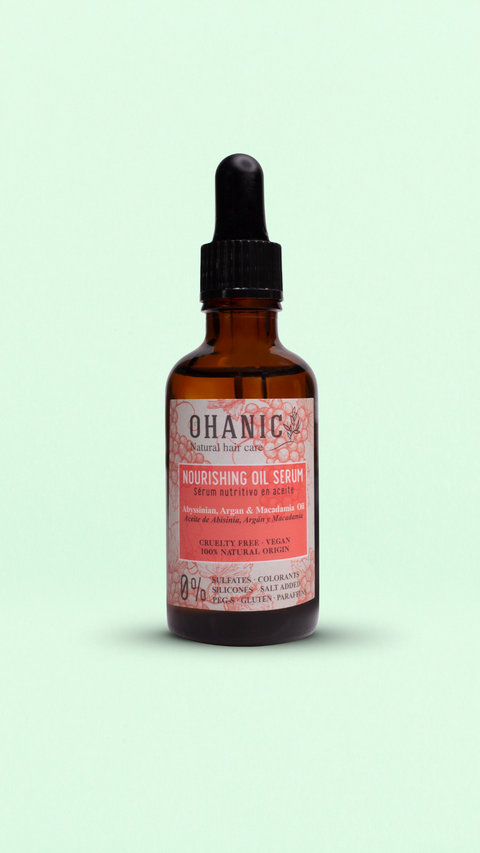 Bild einer braunen Glasflasche mit Pipettenverschluss, die Ohanic Nourishing Oil Serum enthält. Auf dem Etikett steht 'Abyssinian, Argan & Macadamia Oil' sowie 'Cruelty Free, Vegan, 100% Natural Origin'. Das Serum ist frei von Sulfaten, Silikonen, Farbstoffen, Paraffinen und Gluten. Die Flasche hat ein rosa-weißes Etikett mit einem Hinweis auf die natürlichen Inhaltsstoffe.