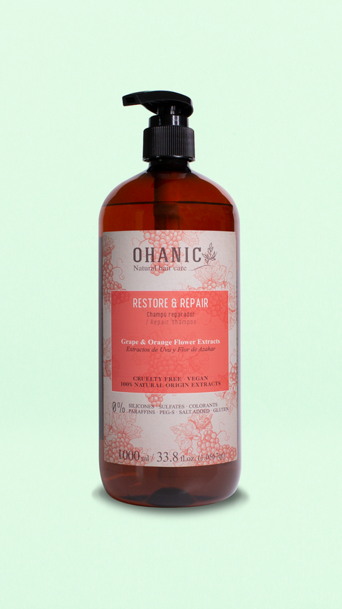 Bild einer 1000 ml Flasche von Ohanic Restore & Repair Shampoo. Die braune Flasche hat ein klassisches Design mit schwarzem Pumpspender und einem Etikett in rosa und weiß. Das Shampoo enthält Extrakte aus Trauben und Orangenblüten, ist cruelty-free und vegan, und besteht zu 100% aus natürlichen Ursprungs-Extrakten. Es ist frei von Silikonen, Sulfaten, Farbstoffen, Paraffinen, PEG-S, Salz und Gluten.