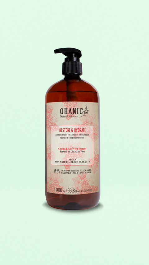 Bild einer 1000 ml Flasche von Ohanic Restore & Hydrate Conditioner. Die braune Flasche hat ein klassisches Design mit schwarzem Pumpspender und einem Etikett in rosa und weiß. Der Conditioner enthält Extrakte aus Trauben und Aloe Vera, ist vegan und besteht zu 100% aus natürlichen Ursprungs-Extrakten. Er ist frei von Silikonen, Sulfaten, Farbstoffen, Paraffinen, PEG-S, Salz und Gluten. 