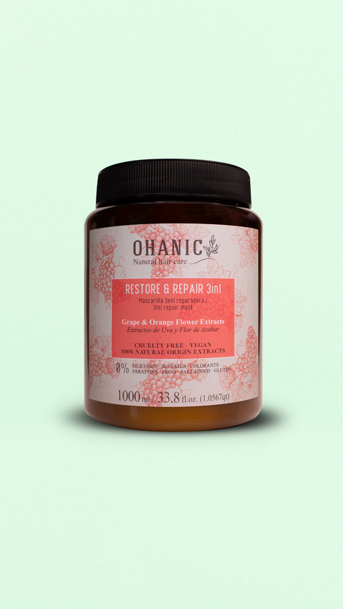 Bild eines 1000 ml Behälters von Ohanic Restore & Repair 3in1 Haarmaske. Der braune Behälter hat ein schwarzes Schraubverschluss-Design und ein Etikett in rosa und weiß. Die Haarmaske enthält Trauben- und Orangenblüten-Extrakte, ist cruelty-free und vegan, und besteht zu 100% aus natürlichen Ursprungs-Extrakten. Sie ist frei von Silikonen, Sulfaten, Gluten, Paraffinen, PEG-S, Salz und Farbstoffen. Auf dem Etikett steht 'Grape & Orange Flower Extracts' und 'Mascarilla 3en1 Reparadora / 3in1 Repair Mask