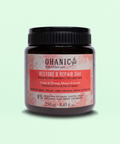 Bild eines 250 ml Behälters von Ohanic Restore & Repair 3in1 Haarmaske. Der braune Behälter hat ein schwarzes Schraubverschluss-Design und ein Etikett in rosa und weiß. Die Haarmaske enthält Trauben- und Orangenblüten-Extrakte, ist cruelty-free und vegan, und besteht zu 100% aus natürlichen Ursprungs-Extrakten. Sie ist frei von Silikonen, Sulfaten, Gluten, Paraffinen, PEG-S, Salz und Farbstoffen. Auf dem Etikett steht 'Grape & Orange Flower Extracts' und 'Mascarilla 3en1 Reparadora / 3in1 Repair Mask