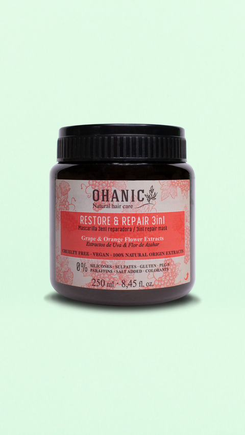 Bild eines 250 ml Behälters von Ohanic Restore & Repair 3in1 Haarmaske. Der braune Behälter hat ein schwarzes Schraubverschluss-Design und ein Etikett in rosa und weiß. Die Haarmaske enthält Trauben- und Orangenblüten-Extrakte, ist cruelty-free und vegan, und besteht zu 100% aus natürlichen Ursprungs-Extrakten. Sie ist frei von Silikonen, Sulfaten, Gluten, Paraffinen, PEG-S, Salz und Farbstoffen. Auf dem Etikett steht 'Grape & Orange Flower Extracts' und 'Mascarilla 3en1 Reparadora / 3in1 Repair Mask